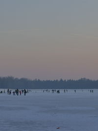 People on beach against sky during winter