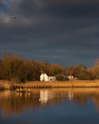 An old english cottage reflecting on a lake during a storm