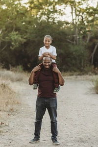 Portrait of school-aged son sitting on father's shoulders