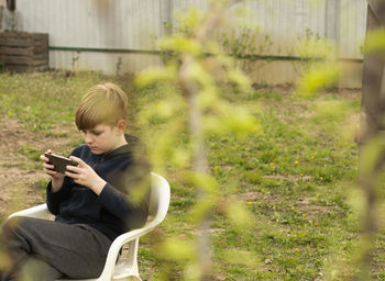 Young man using mobile phone while sitting outdoors