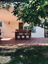 Empty bench by building against trees