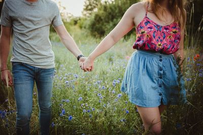 Midsection of couple holding hands while standing on land