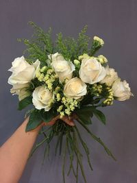 Close-up of hand holding white roses