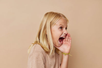 Cute girl screaming against beige background