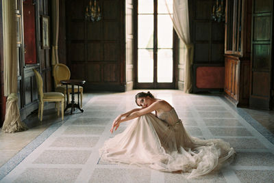 Side view of woman sitting on floor