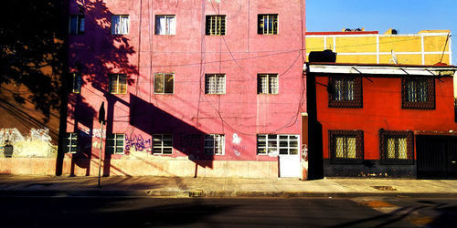 Residential buildings by street in town against sky