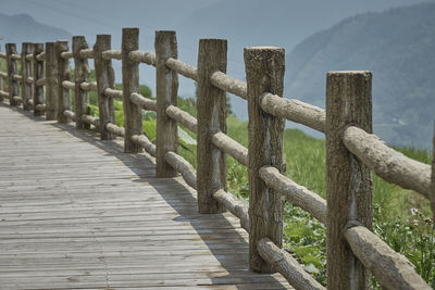 Wooden fence on boardwalk against sky