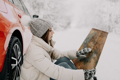 Side view of woman in snow covered car