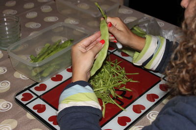 Cropped image of woman cutting vegetable at table