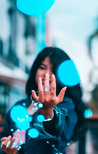 Portrait of young woman standing against blurred background