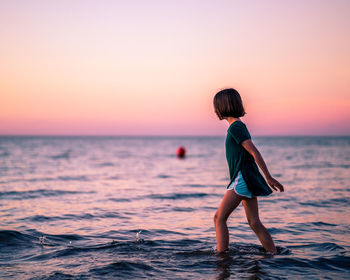 Full length of woman standing on beach during sunset