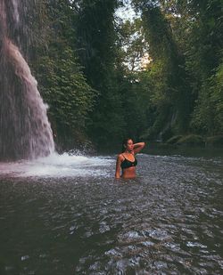 Man sitting by waterfall in forest