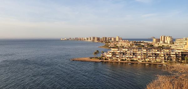 Scenic view of sea by buildings against sky