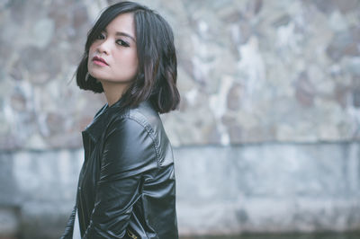 Portrait of young woman standing against water