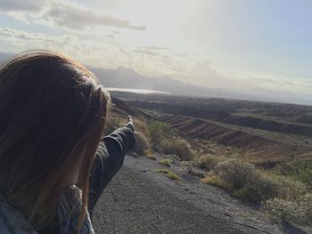 Close-up of woman pointing at landscape against sky