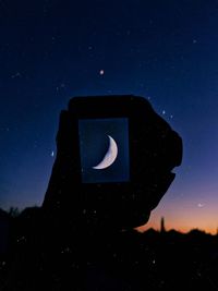 Close-up of silhouette information sign against sky at night