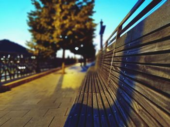 Close-up of footpath by railing against blue sky