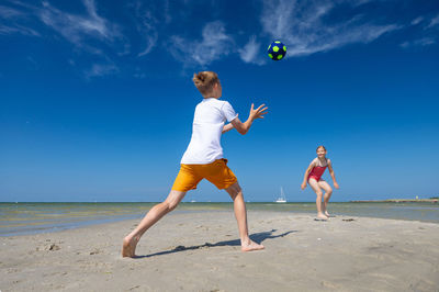 Full length of friends enjoying at beach against sky