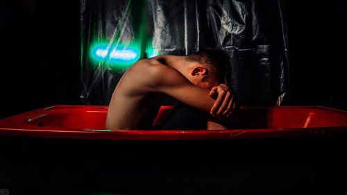 Side view of shirtless young man sitting in bathtub