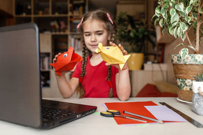 Portrait of girl using laptop on table at home