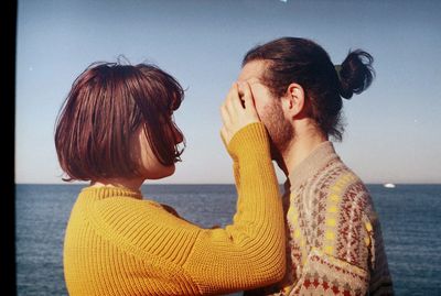 Side view of young woman at beach against sky