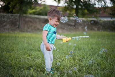 Full length of cute boy playing on grassy field at park