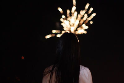 Rear view of woman looking at firework display at night