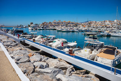 Boats moored at harbor against clear blue sky