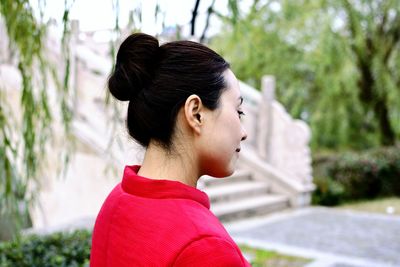 Thoughtful young woman with hair bun against steps