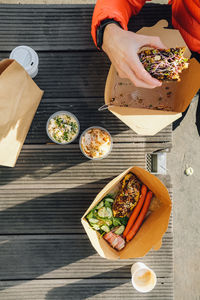 High angle view of male hand holding food outside, take away breakfast.