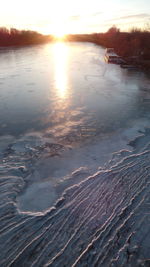 Scenic view of frozen lake against sky during sunset