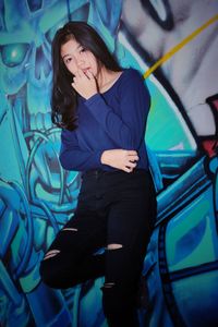 Young woman looking away against wall