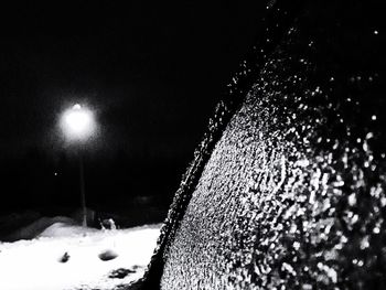 Close-up of illuminated snow against sky at night