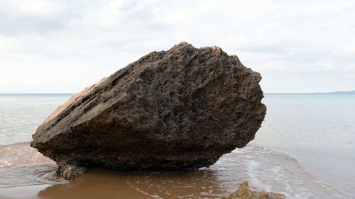 Rock formation on beach against sky