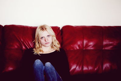 Portrait of young woman sitting on sofa at home