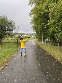 Full length of mature woman standing on road against sky