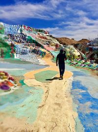Rear view of man standing on mountain against sky