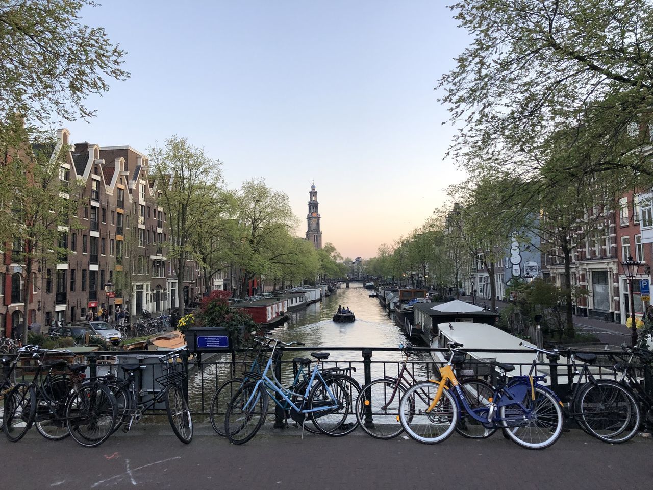 BICYCLES PARKED BY CANAL IN CITY AGAINST SKY