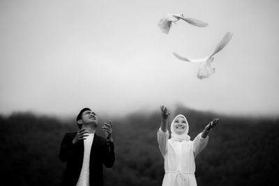 Low angle view of woman with arms raised against clear sky