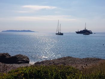 Sailboats in sea against sky