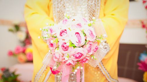 Midsection of bride holding flower bouquet