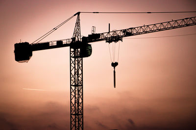 Low angle view of silhouette crane against sky during sunset