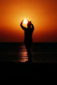 Silhouette man standing at beach during sunset