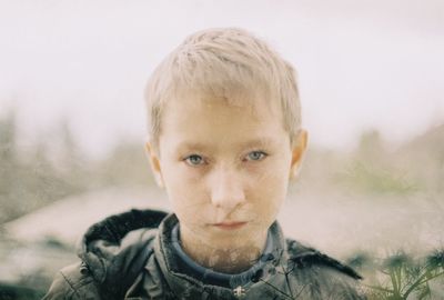 Double exposure image of trees and serious boy