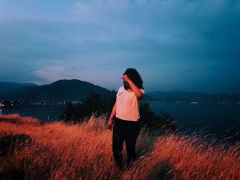 Rear view of woman standing on land against sky