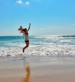 Woman standing at beach against sky