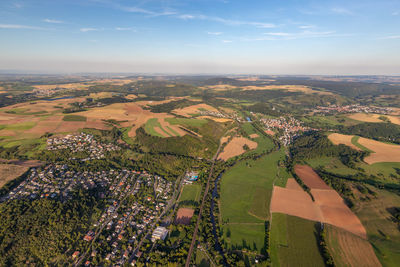 Aerial view of agricultural field by buildings against sky