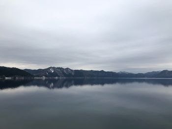 Scenic view of lake by mountains against sky