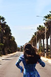 Rear view of woman standing on road against sky