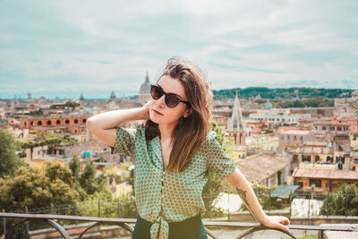 Portrait of young woman wearing sunglasses standing against sky